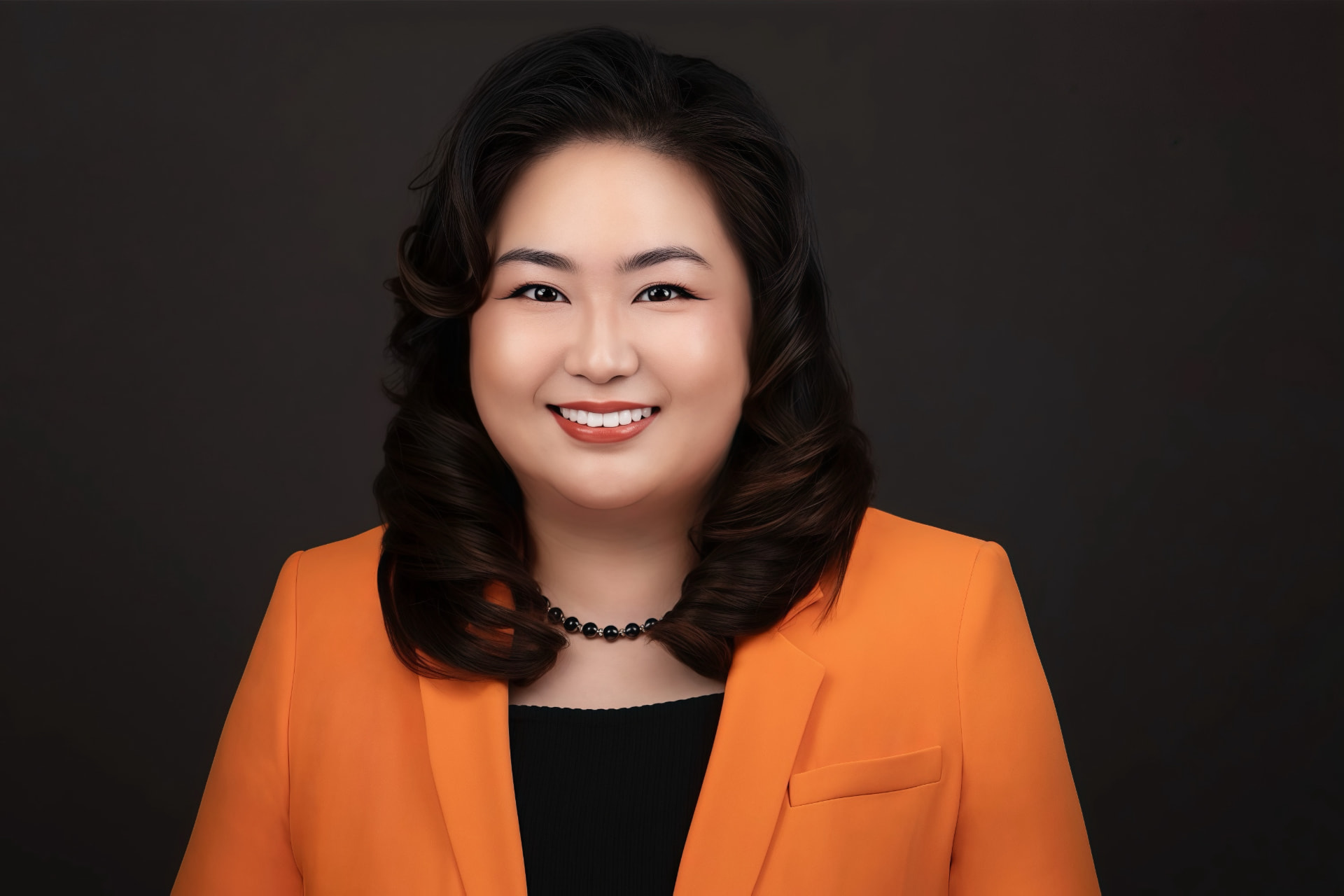 Portrait of Yvonne Zhao, founder of Báistiez Nails Club, smiling in an orange blazer